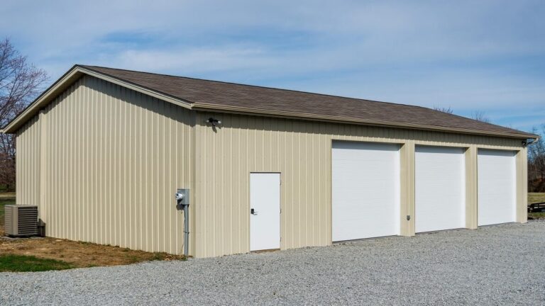 30x33 pole barn garage with light yellow metal siding, three white garage doors, and a brown roof