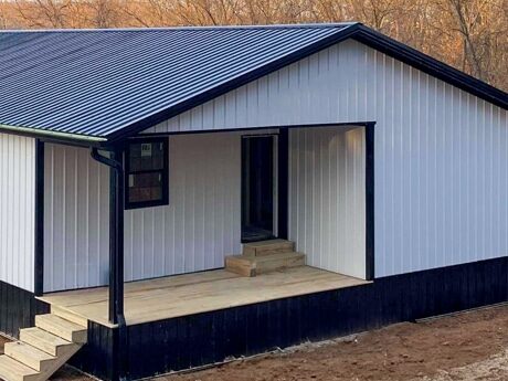 30x70 white and black trimmed barndominium with side entrance with porch and black metal roofing