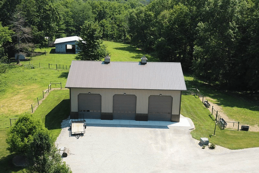 40x40 pole barn garage with tan siding brown metal roof three brown overhead doors and brown paneling around the bottom