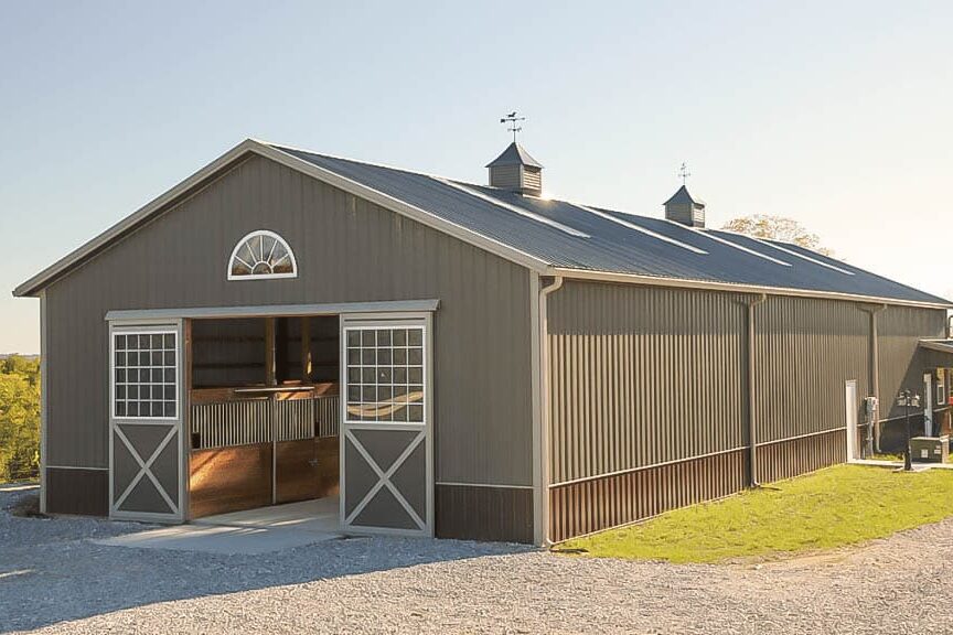 40x64 gray agricultural pole barn being used to house horses