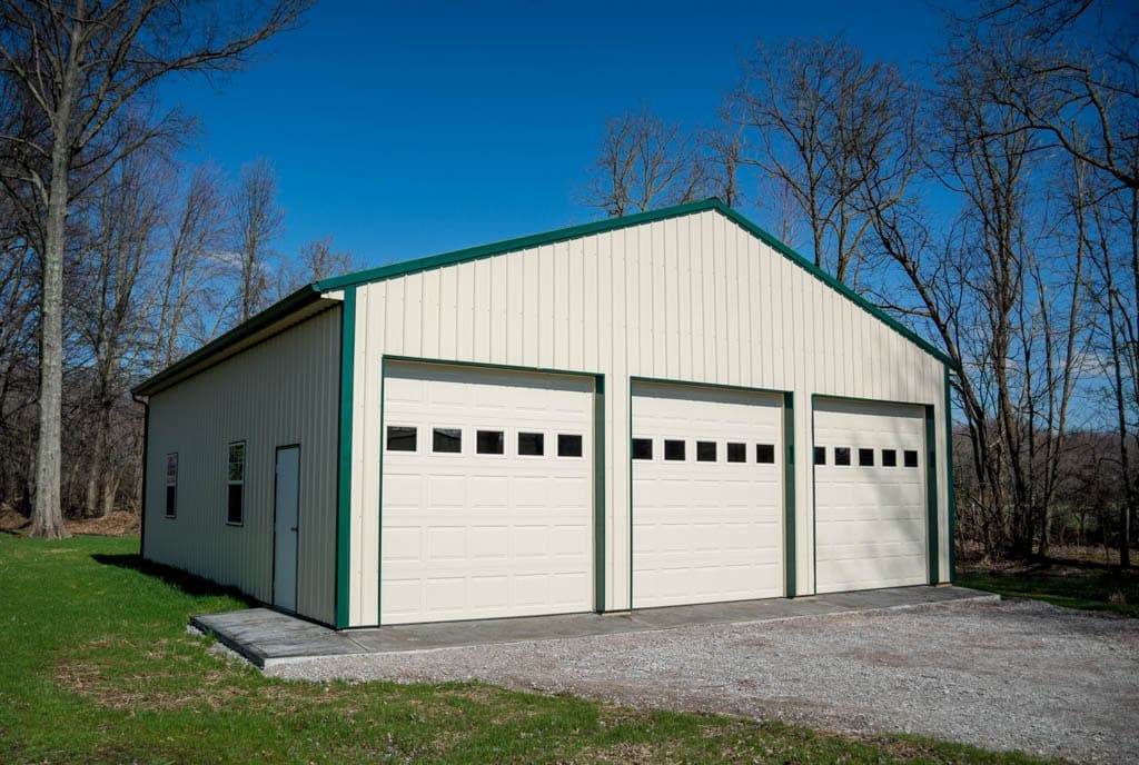 white pole barn garage with green trim and green roof with three garage doors in Richmond IN