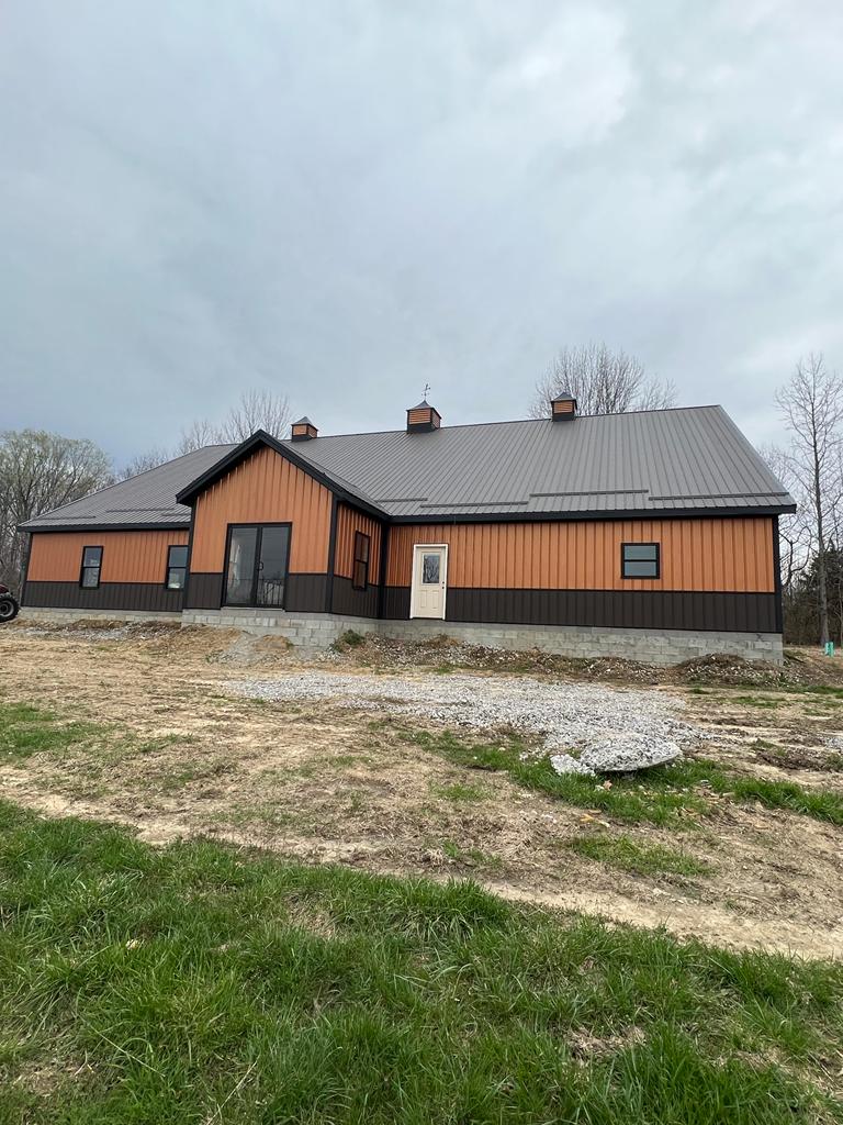 An orange and black 80x100 commercial pole barn with a metal roof