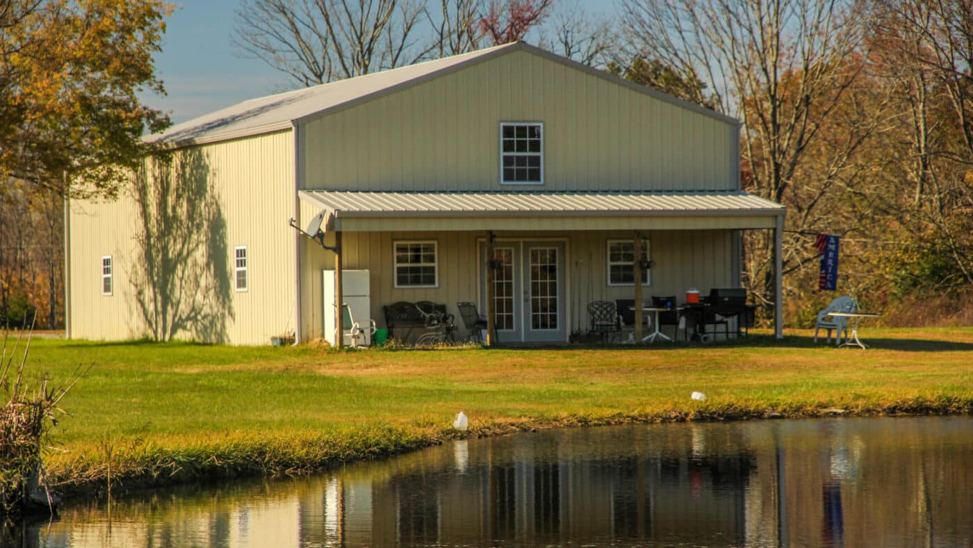 A white 80x120 barndominium right by a lake