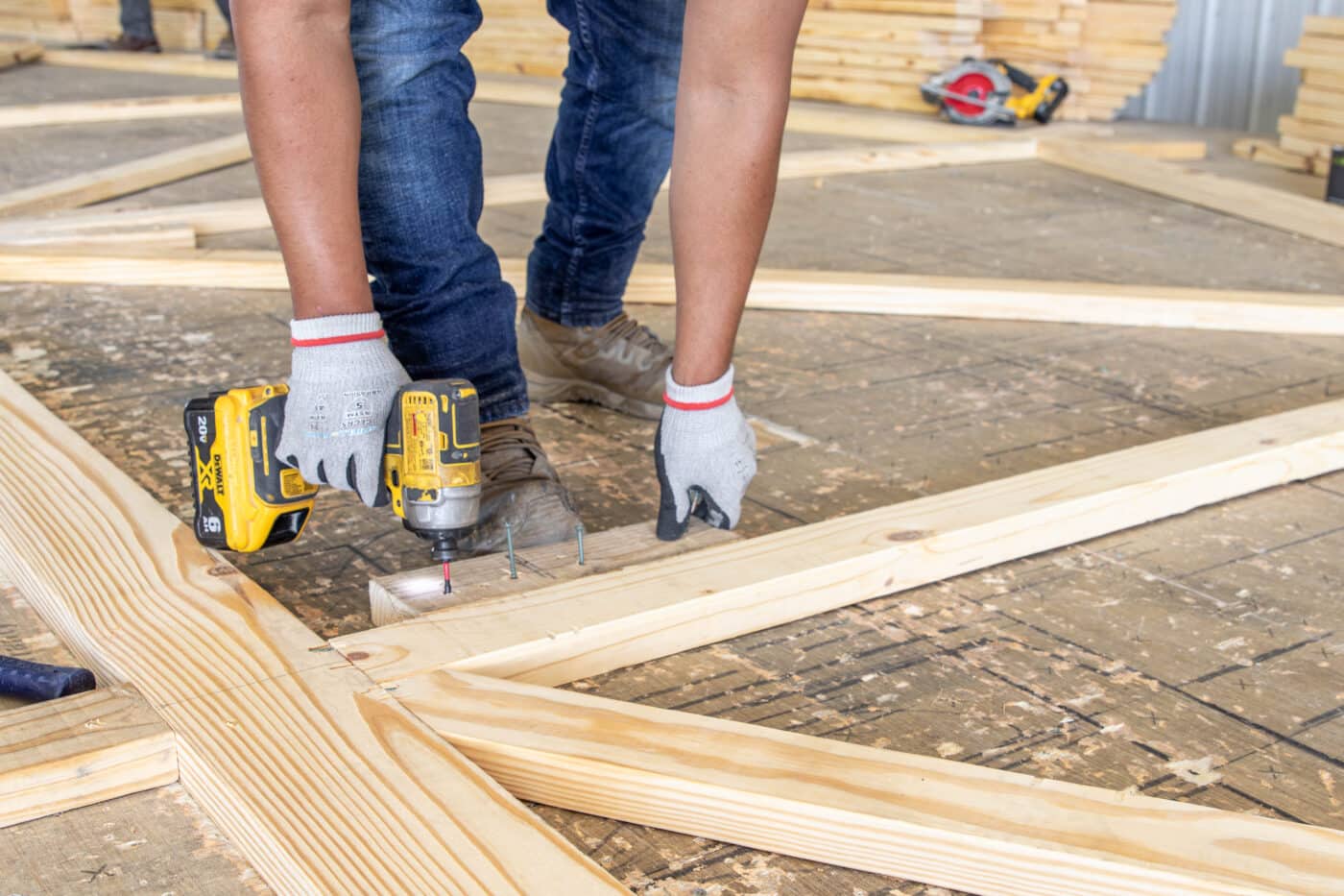 A man drilling into roof trusses for 80x120 commercial pole barns