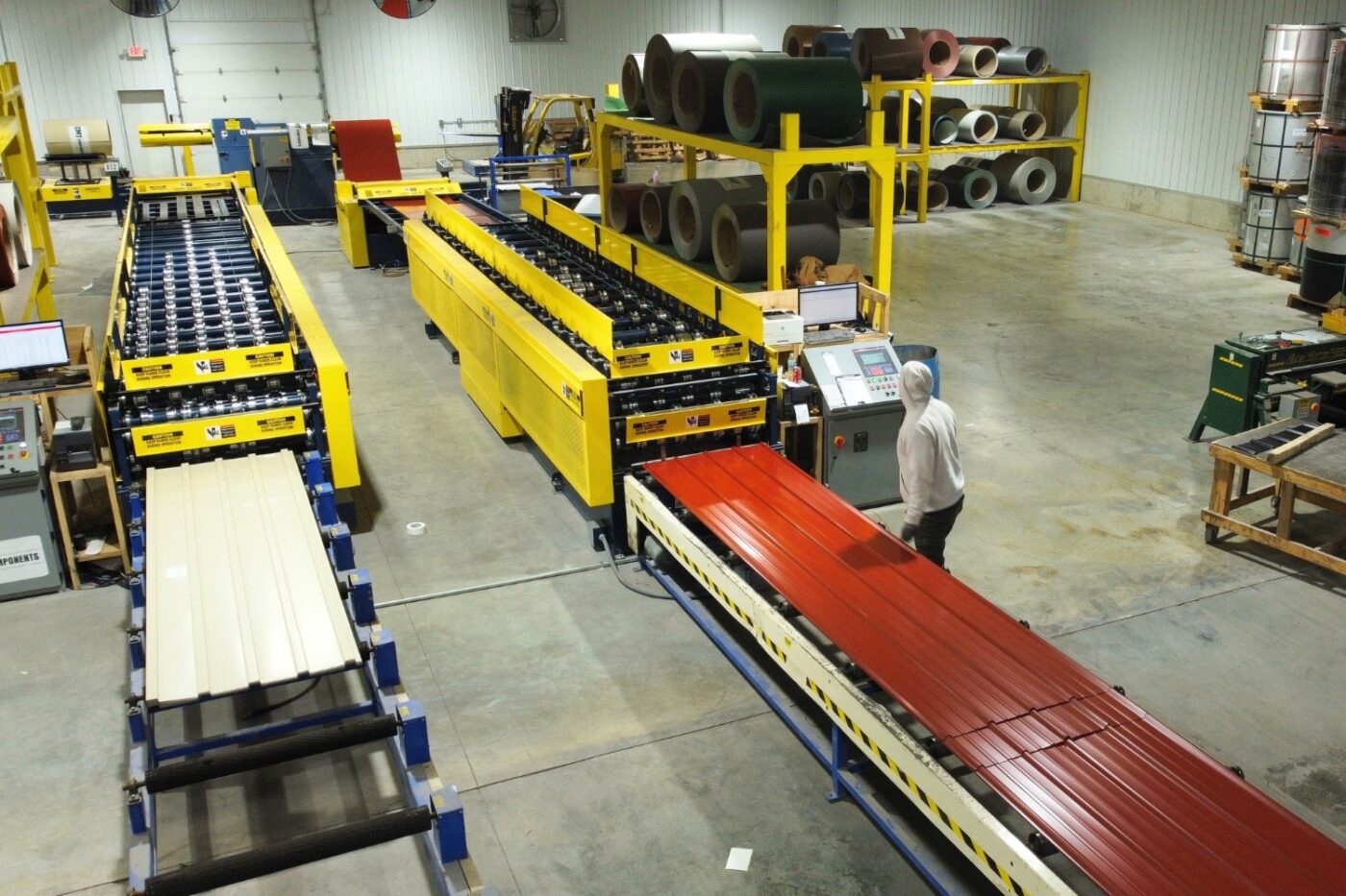 man manufacturing red metal panels for 80x90 pole barn garage kits