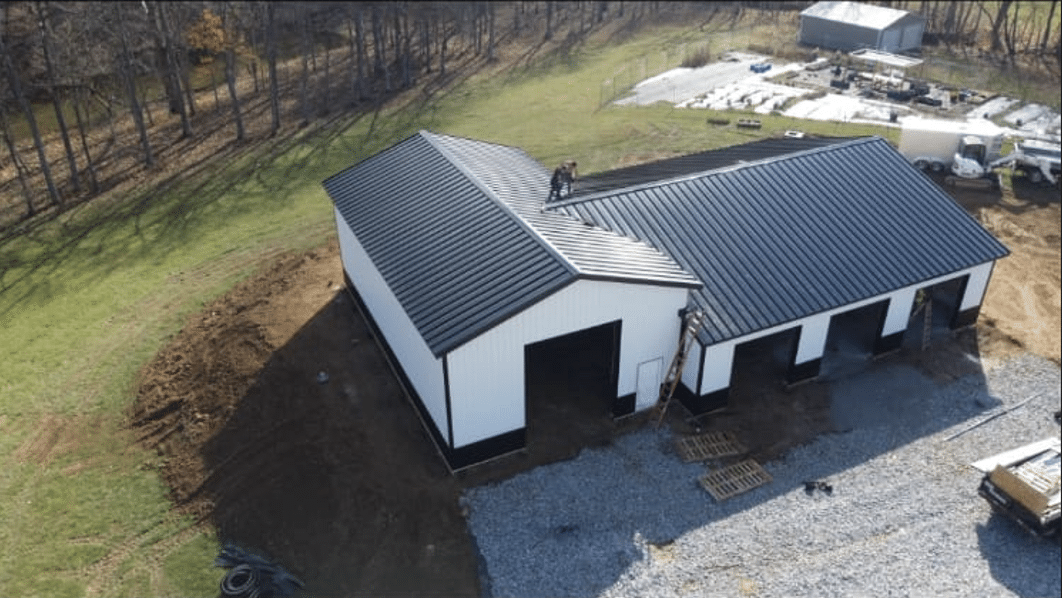 white pole barn garage with three garage doors, black trim and a black roof in McArthur OH