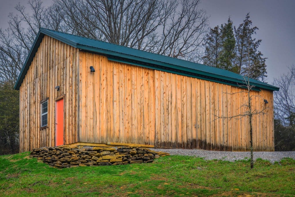 Wooden Pole Barn Kits in Brooksville KY with green roof and orange door