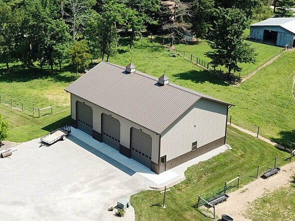 aerial side view of tan and brown 40x60 pole barn garage with three doors