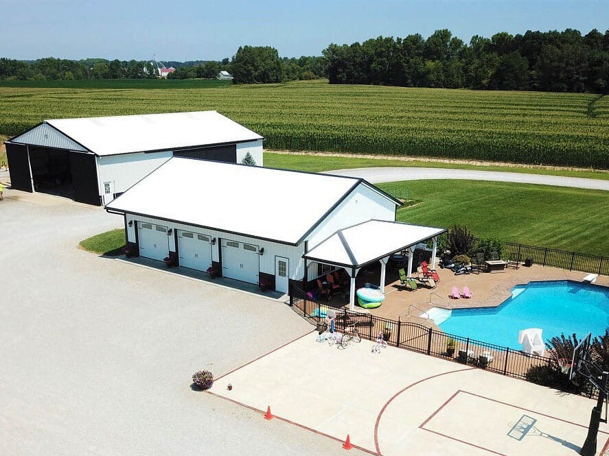 aerial view of white and black trimmed three car 30x33 pole barn garage beside pool