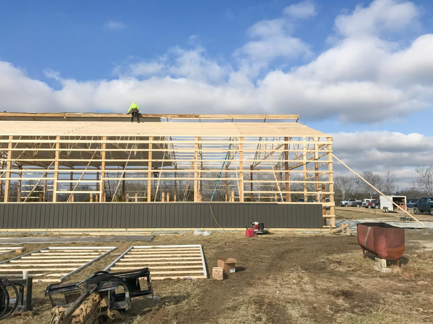 agricultural pole barn frame with metal roofing being laid