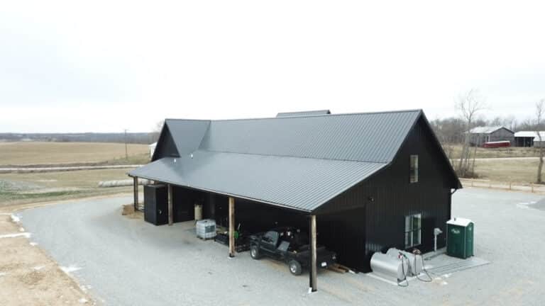 all black 30x70 barndominium with cars parked under overhang