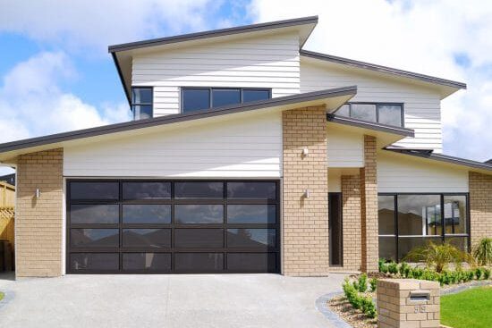 black aluminum garage door on white and brick house