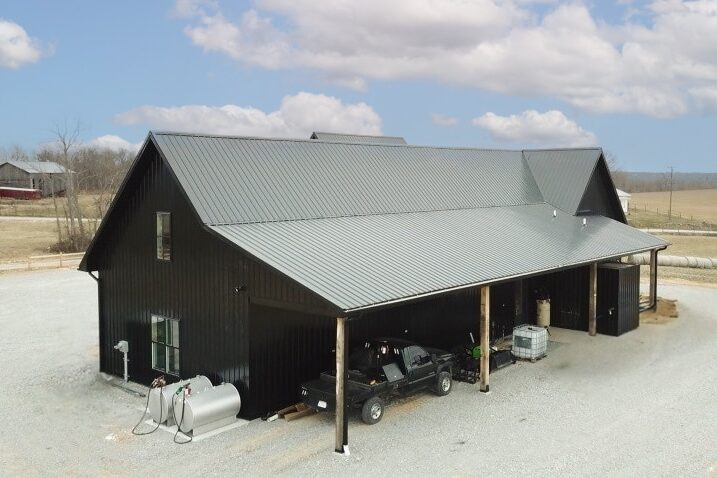 black barndominium with side overhang with cars parked underneath what is a barndominium kit