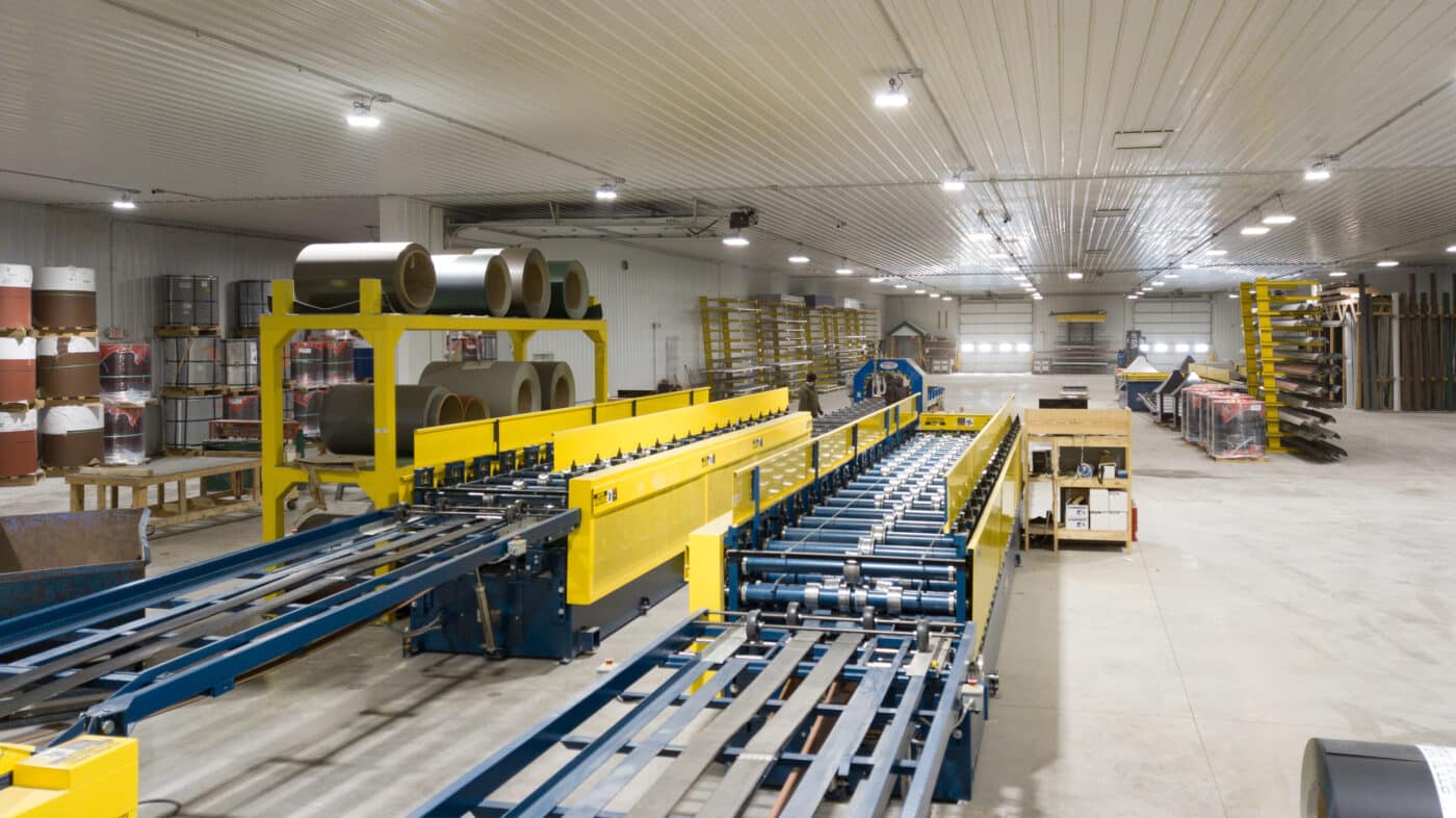 blue and yellow assembly line machines for manufacturing metal components for barndominium kits
