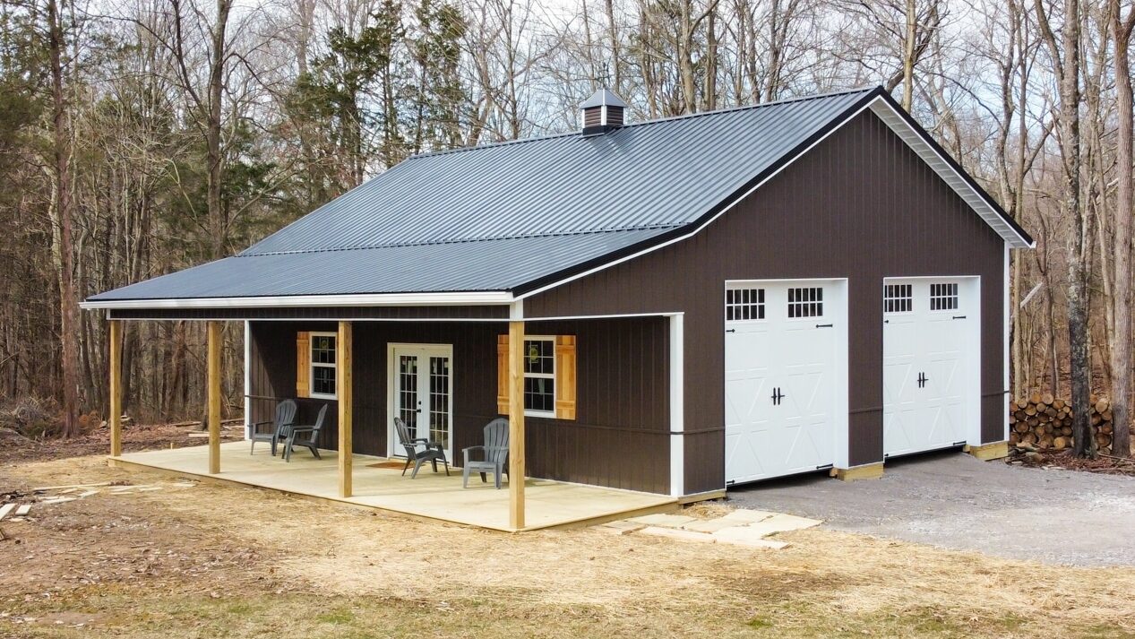 brown 30x33 pole barn garage with two white garage doors and a front porch