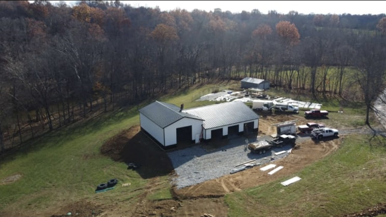 contractors working on putting together a white and black metal pole barn
