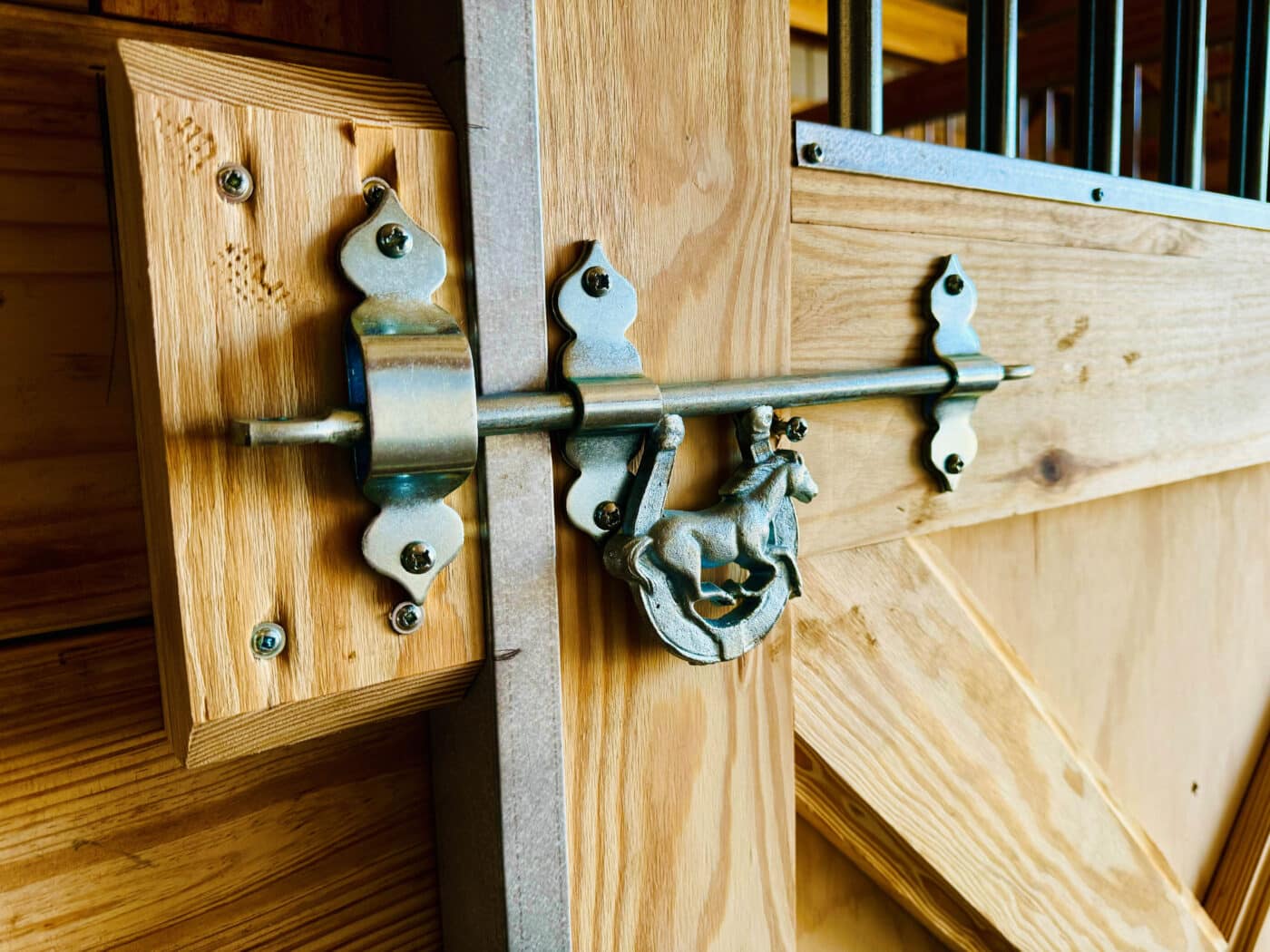 custom horseshoe with horse in it latch on wooden stall door inside agricultural pole barn