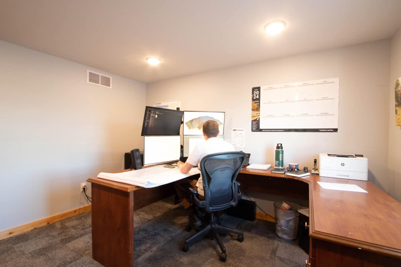 A man in an office looking at multiple screens providing customer service for people purchasing 30x40 equestrian pole barn kits