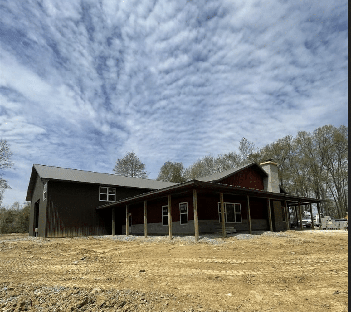 A dark 100x120 commercial pole barn in a field