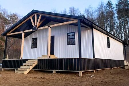 front of white and black trimmed 32x56 barndominium with porches