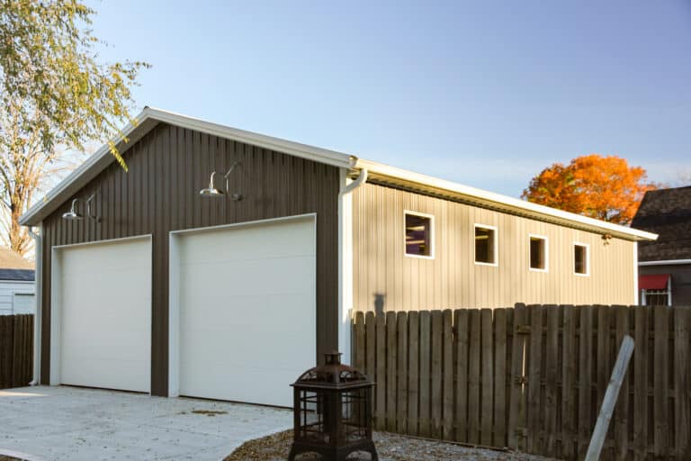 gray 24x36 garage pole barn with two white garage doors and overhead lights and 4 windows on the side