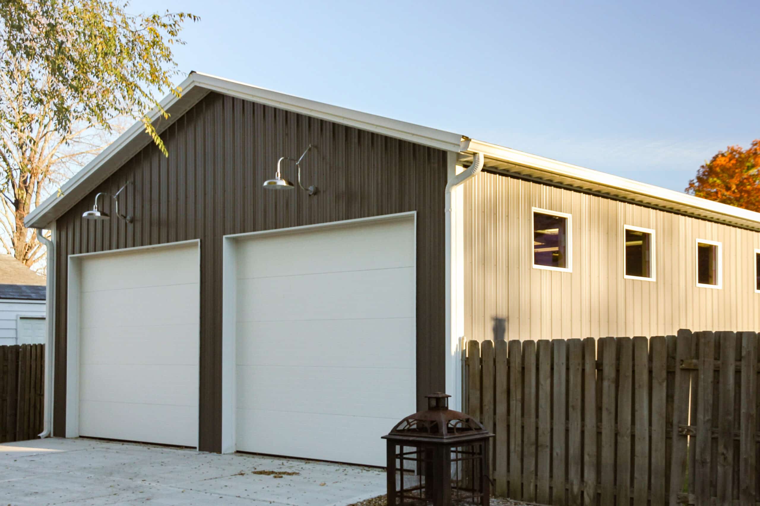 gray metal pole barn with two white overhead doors and two overhead lights over each