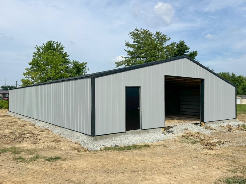 gray sided 40x60 pole barn with black roofing and side door by opening for garage door