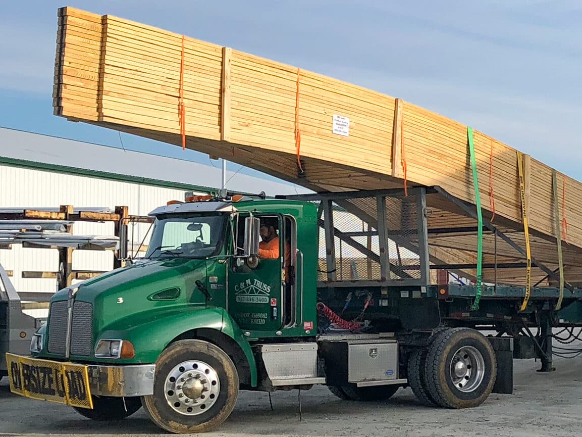 green CMT Components truck with wooden roof trusses strapped to back for 24x40 pole barn garage