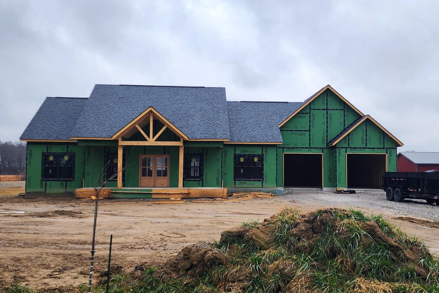 green wrapped barndominium with shingle roof in the process of being built