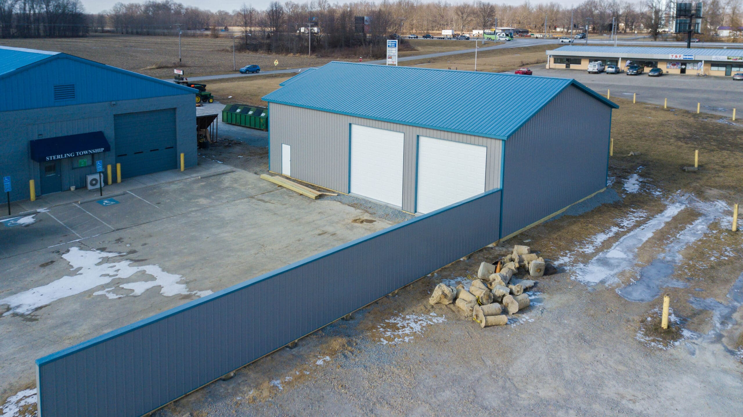 gray 30x48 garage pole barn kit with blue roof and two white garages