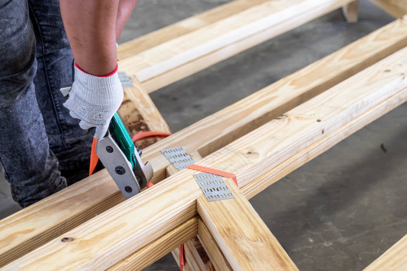 man cutting ties off wooden roof trusses
