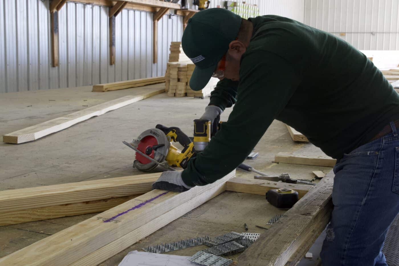 a man working on roof trusses for 25x50 commercial pole barn kits
