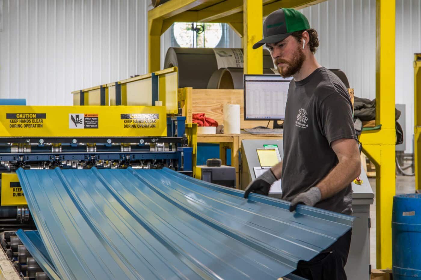 man manufacturing blue metal panels for 32x40 pole barn garage at yellow machine