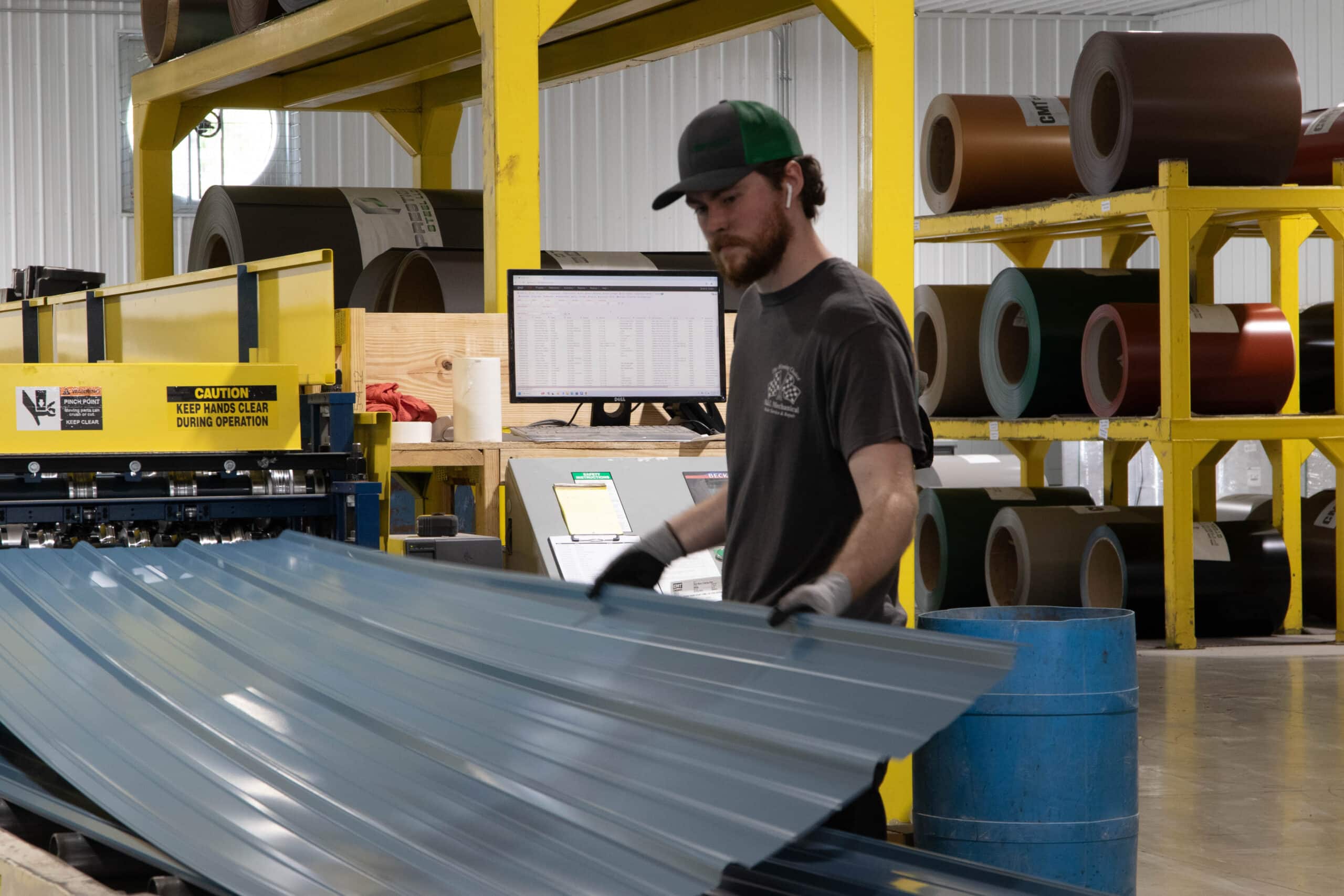 man pulling blue metal panel out of machine