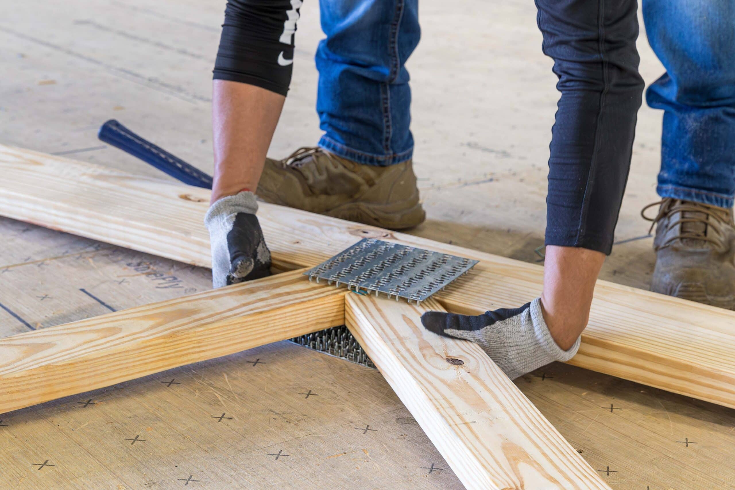 man putting together wooden roof trusses