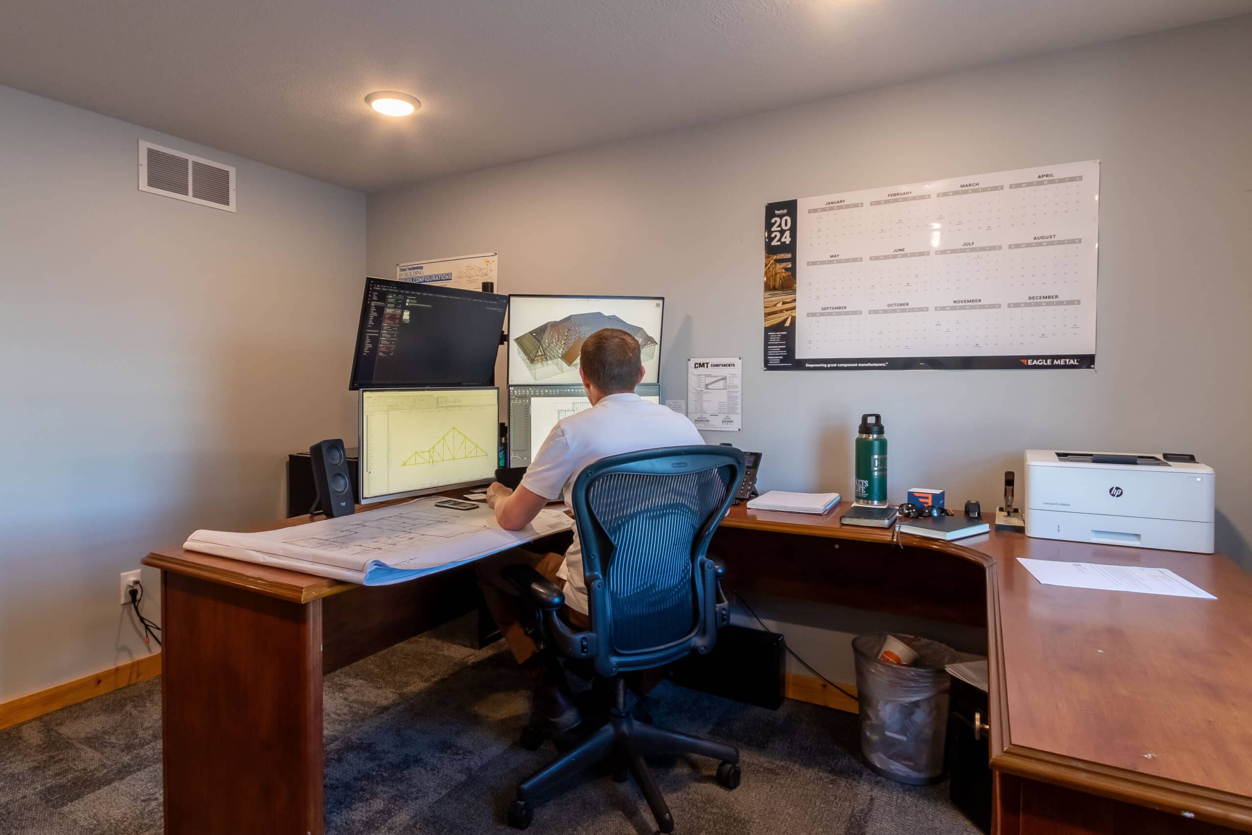 man sitting at desk with multiple computers working on the design for a 30x30 barndominium