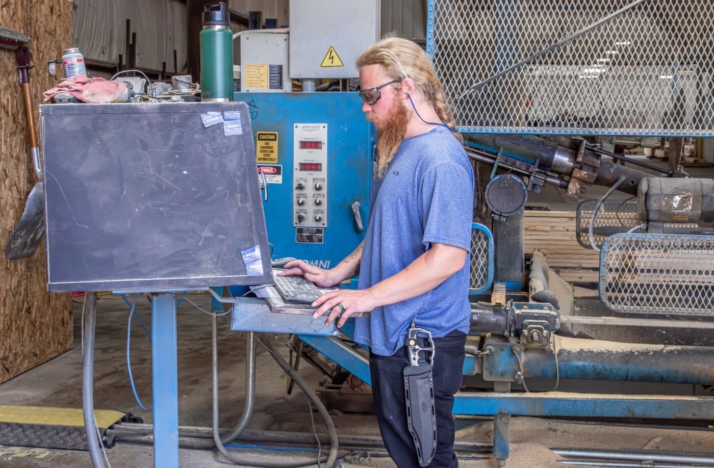 man typing in pole barn specifications on computer to begin custom manufacturing components to assemble the kit