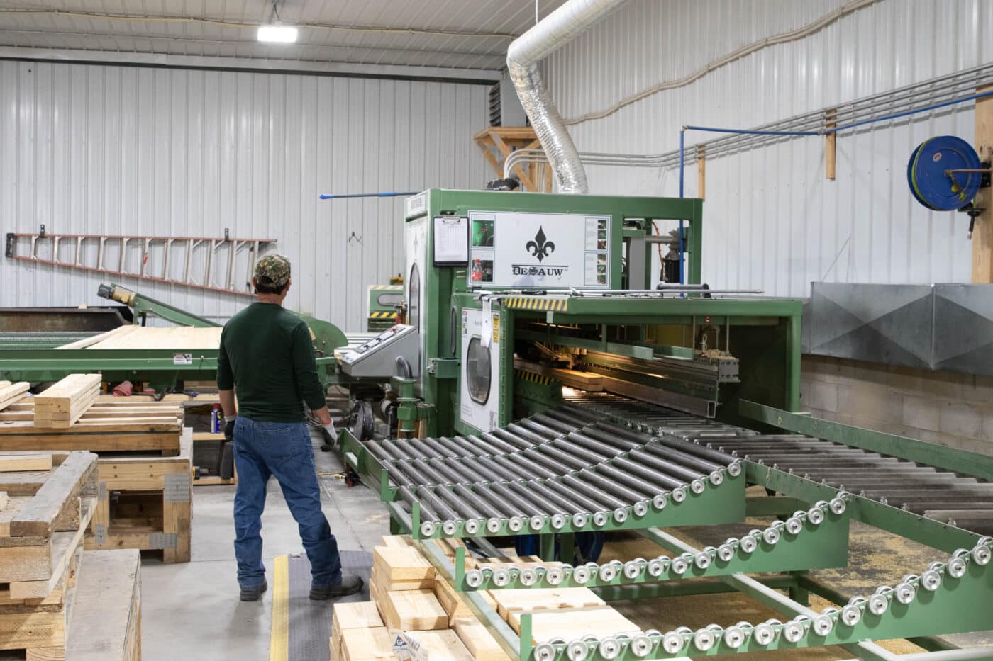 A man using a machine to cut trusses for 30x100 barndominiums