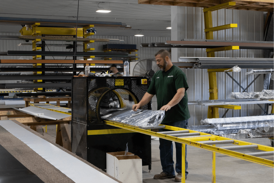man wrapping black metal panel for 70x100 pole barn garage kit