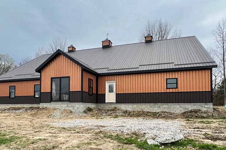 orange metal sided commercial pole barn on concrete block foundation with black trim brown metal bottom trim and black metal roof