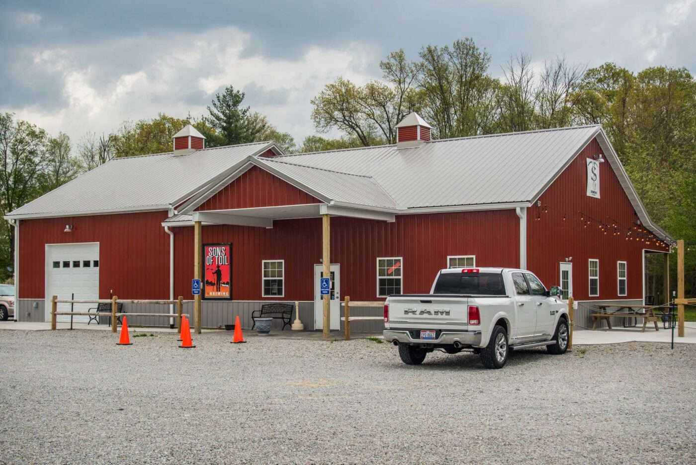 A red 60x100 commercial pole barn with a white roof and a white truck parked outside