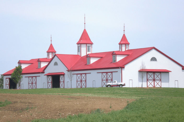 white 100x150 equestrian pole barn kit with red metal roof and cupolas