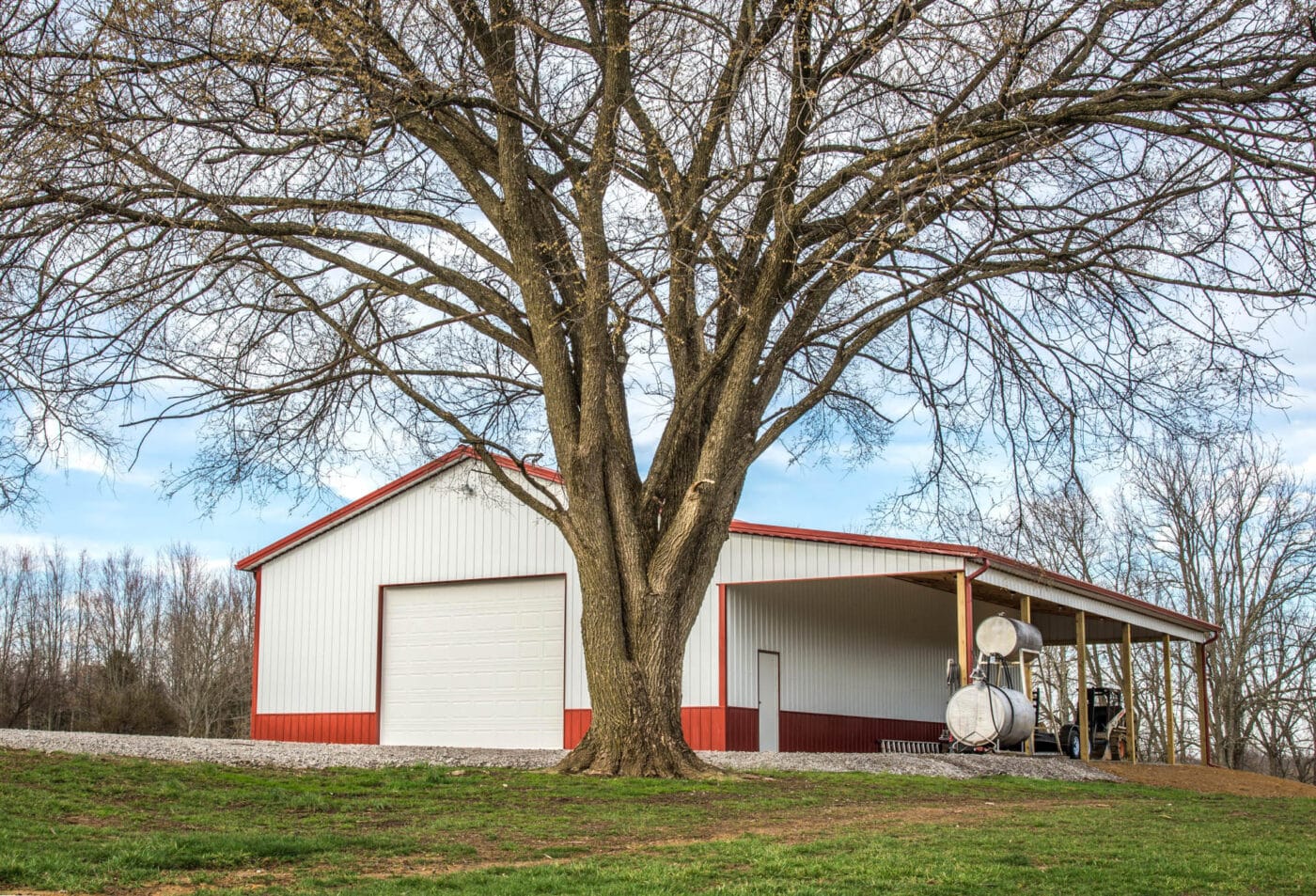 red and white 24x32 agricultural pole barn by tree