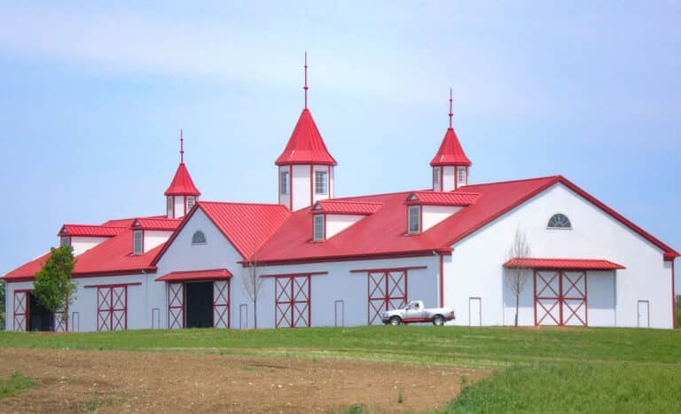 red and white 36x36equestrian pole barn with three large circular posts with windows and multiple doors