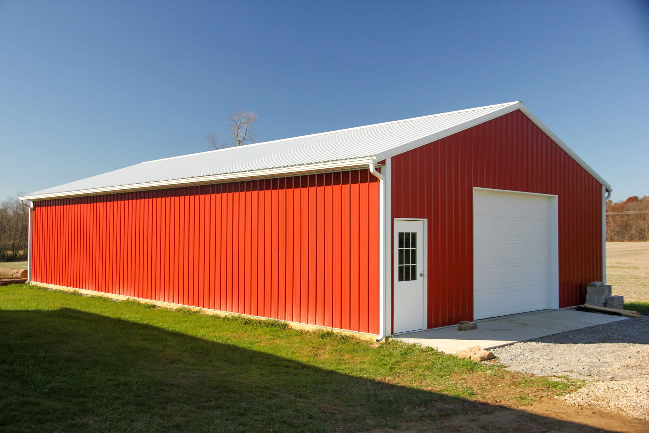 red pole barn garage with white metal roof and one white overhead garage doors