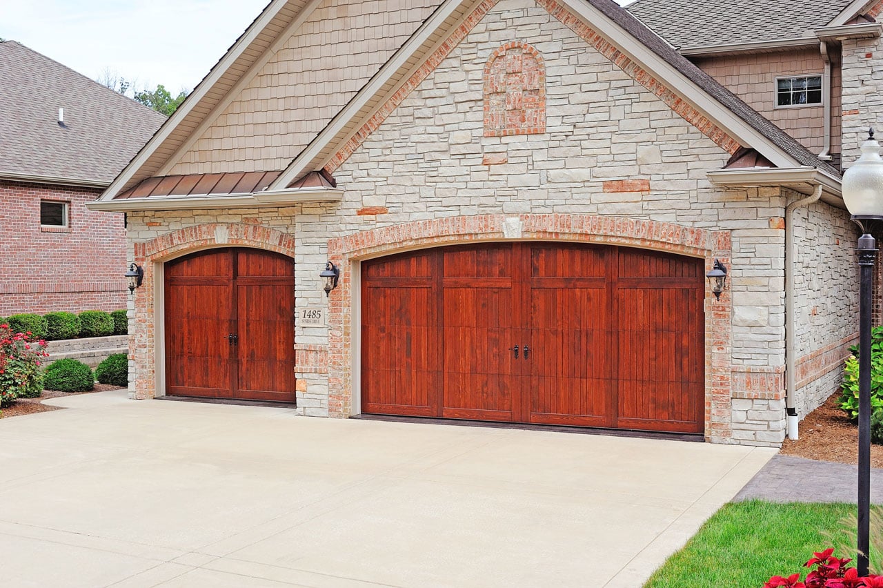 reddish colored wood garage doros on stone home