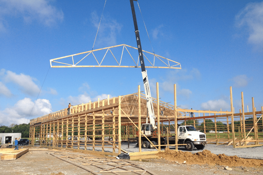 roof truss being lowered onto pole barn garage frame