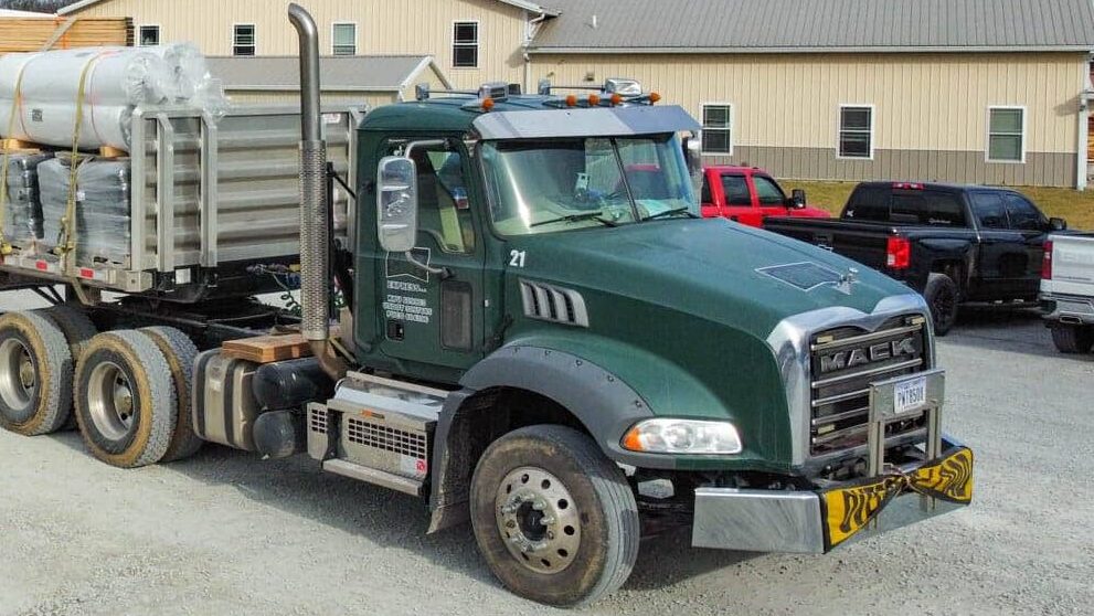 roof trusses being delivered on back of green truck