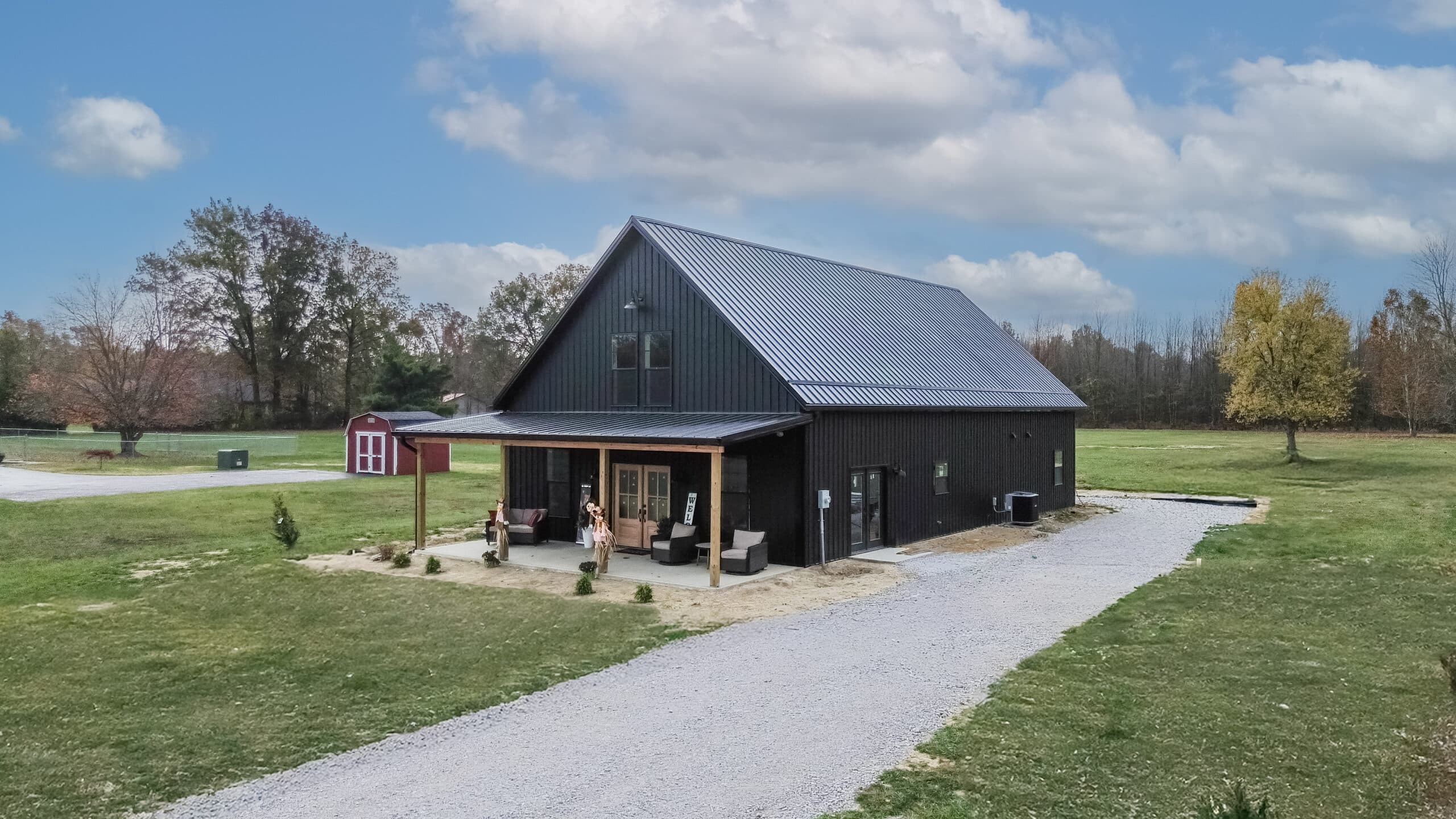 side angle of 40x80 black barndominium with front porch featuring an overhang
