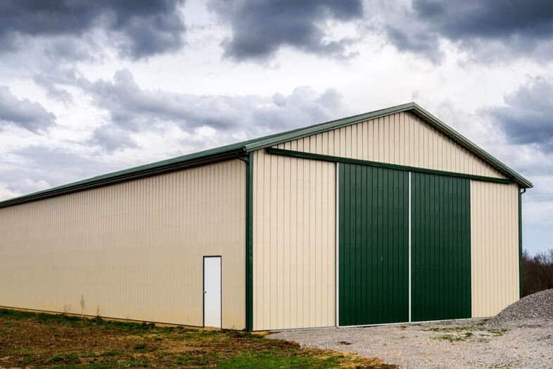tan agricultural pole barn with green doors